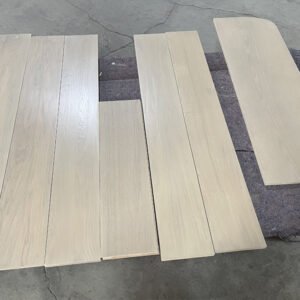 Light-toned red oak stair components arranged on padding, showing rectangular pieces and a shaped piece