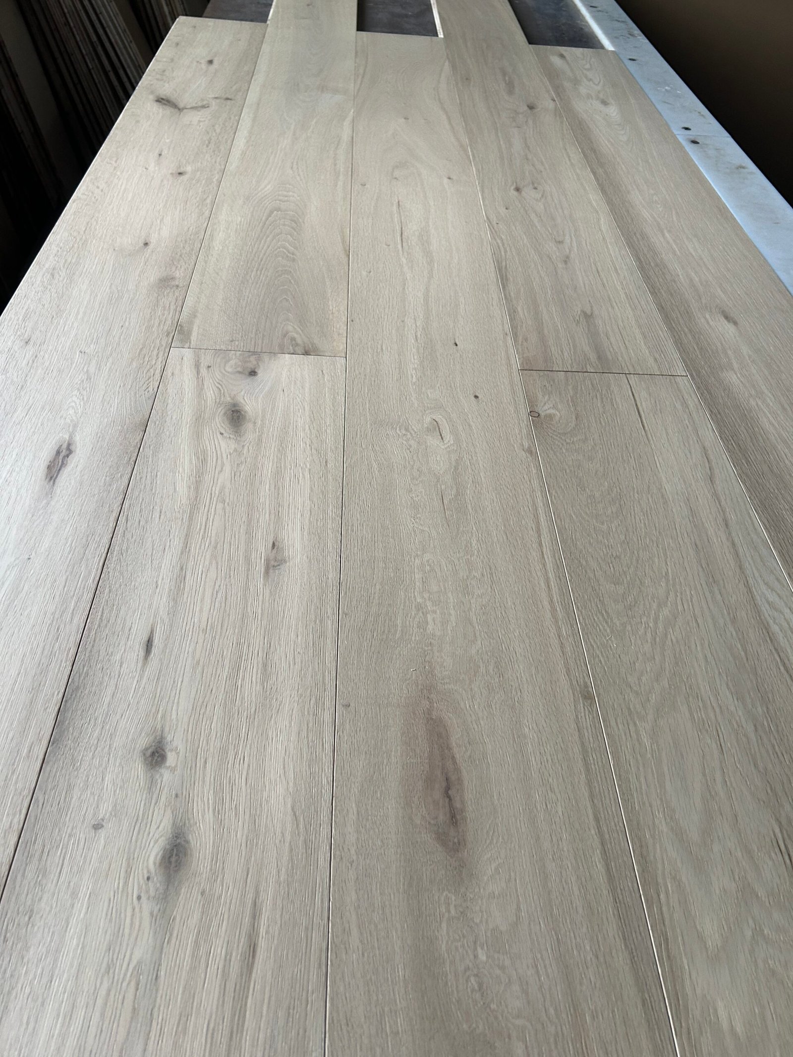 Pearl Beige engineered oak flooring boards showing light beige-gray tones, visible knots, and natural grain variation