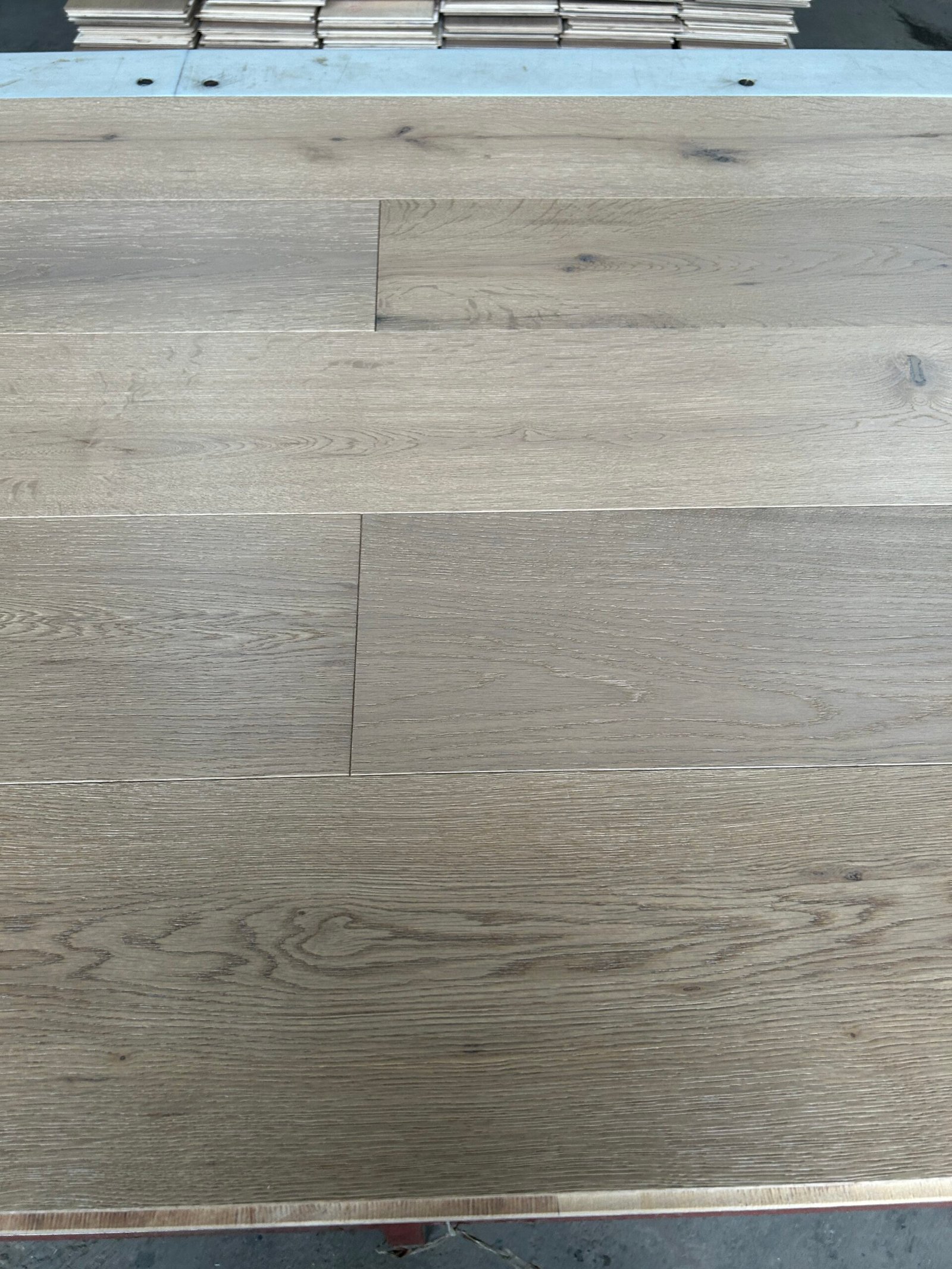 Close-up of Linen Beige oak flooring showing grain patterns, small knots, board joints, and tonal variation