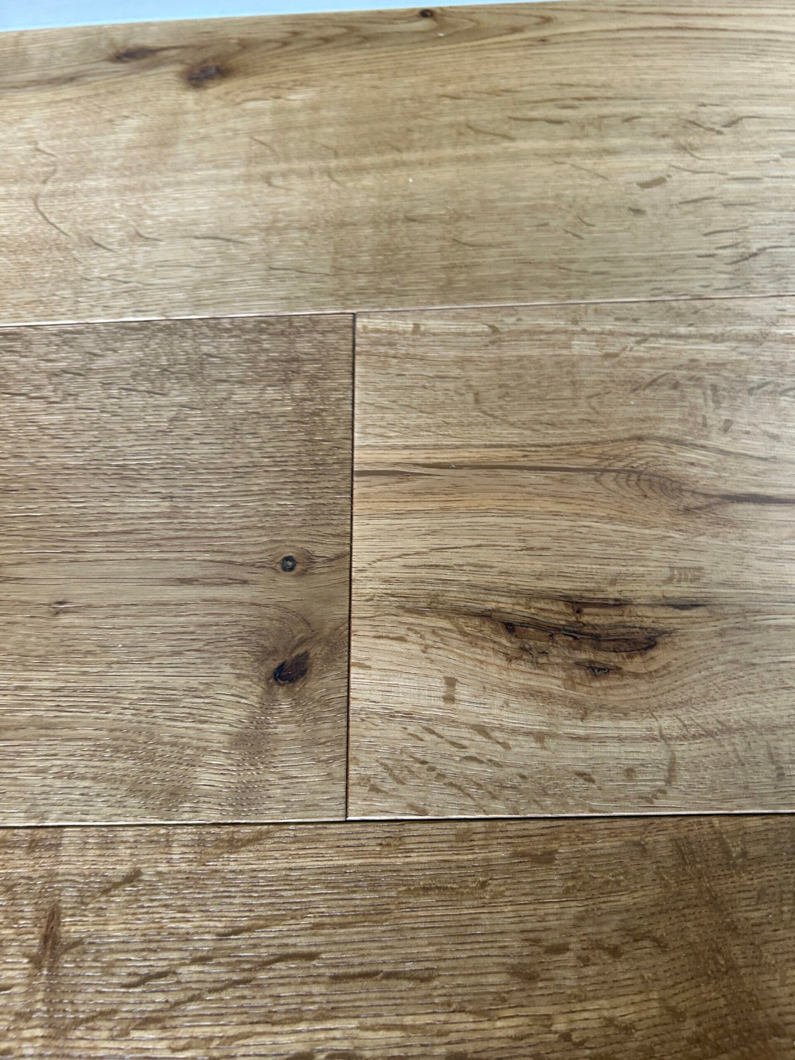 Close-up of Warm Wheat oak flooring showing dark knots, contrasting grain, and board joints
