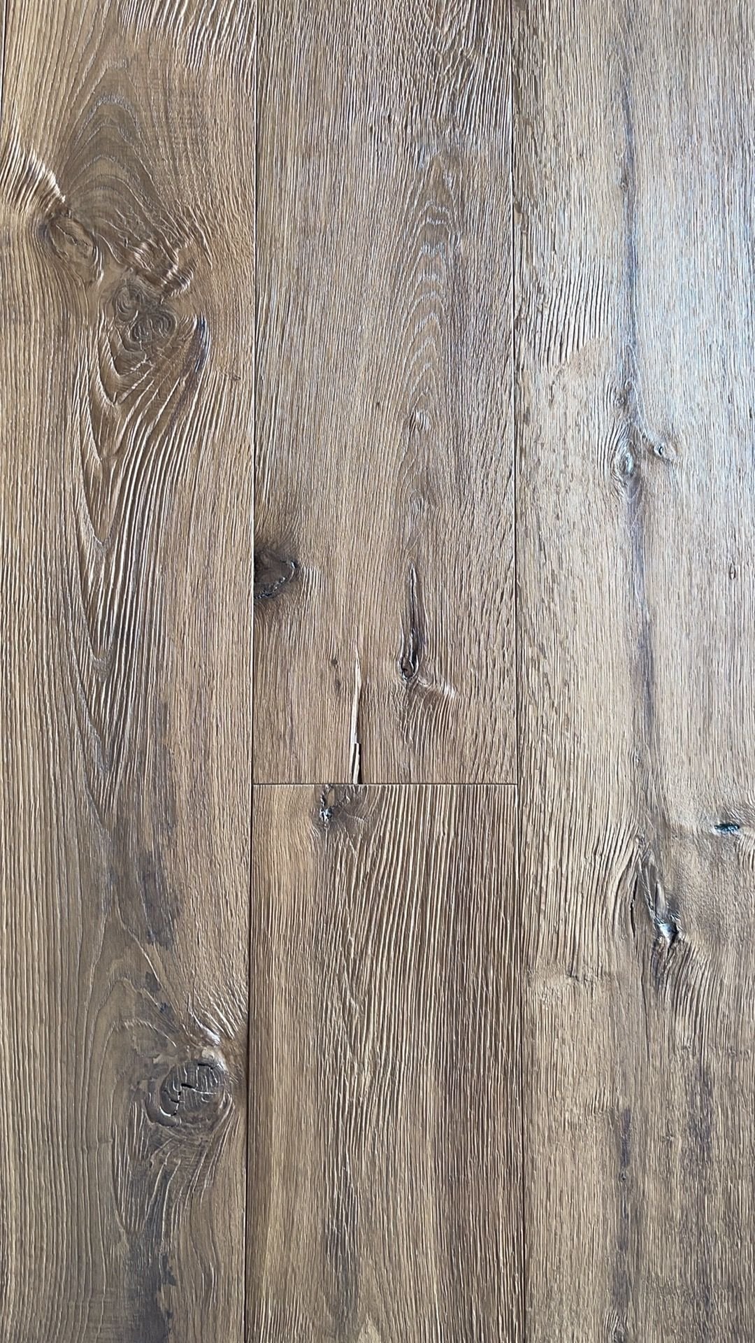 Axe hewn oak flooring showing textured grain, visible knots, and variation across adjacent boards